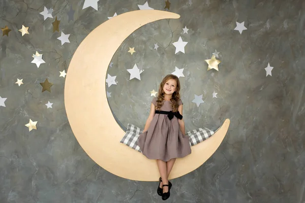 Malá holčička v sedí na velké měsíc. Malá holčička sní — Stock fotografie