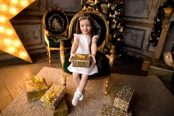 Маленька усміхнена дівчина з різдвяною подарунковою коробкою . — стокове фото