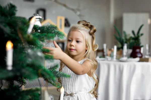 Feliz Navidad y Felices Fiestas. Linda niña decora un árbol de Navidad . — Foto de Stock