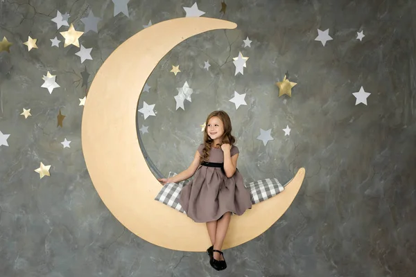 Little girl in sitting on big moon. Little girl dreaming — Stock Photo, Image