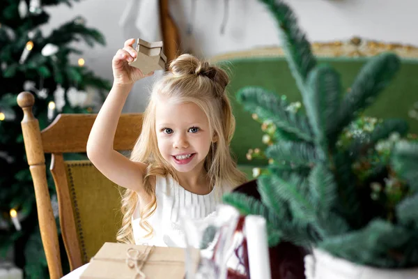 Feliz Navidad y Felices Fiestas. Alegre linda niña abriendo un regalo de Navidad . — Foto de Stock