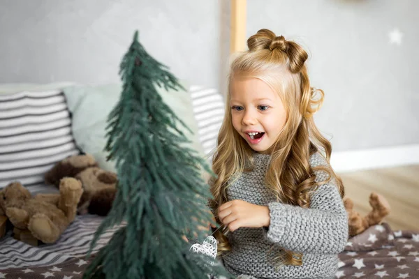 Feliz Navidad y Felices Fiestas. Linda niña decora un árbol de Navidad . — Foto de Stock