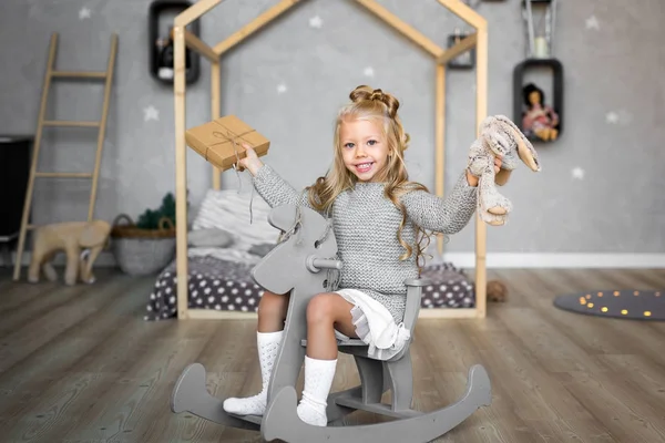 Милая маленькая девочка верхом на игрушечной лошади — стоковое фото