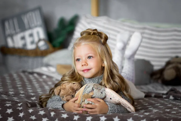 Linda niña está jugando con un oso de juguete en la cama — Foto de Stock