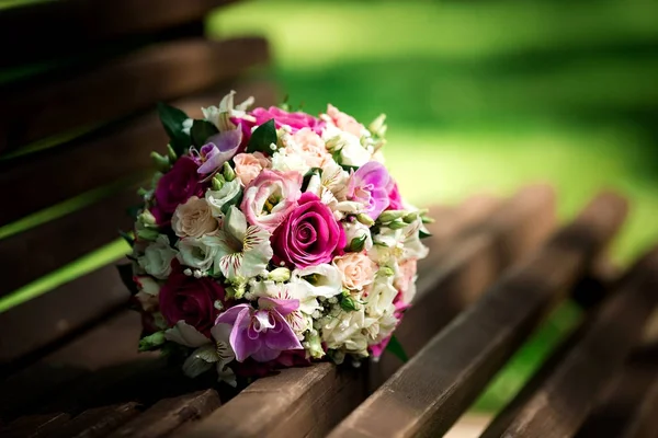 Svatební kytice z růžových a bílých růží ležících na trávě — Stock fotografie
