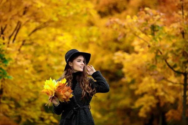 Kvinna med hösten lämnar i hand och faller gula lönn trädgård bakgrund — Stockfoto