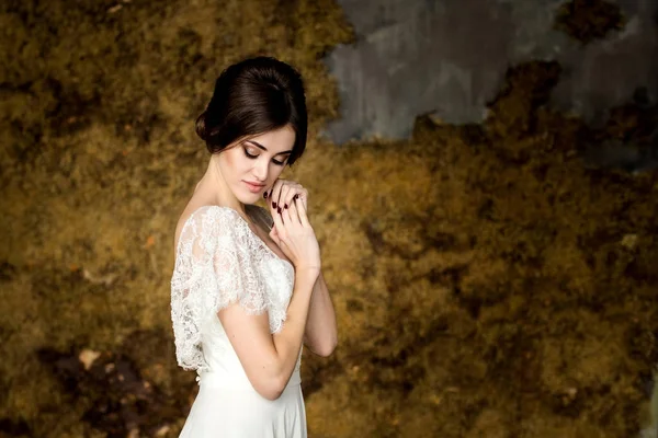 Bride in white dress sitting on chair indoors in dark studio interior like at home. — Stock Photo, Image