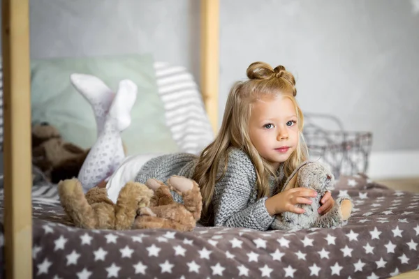 Linda niña está jugando con un oso de juguete en la cama — Foto de Stock