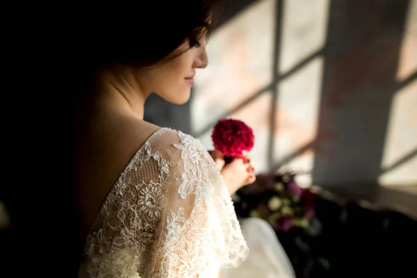 Noiva em vestido branco sentado na cadeira dentro de casa em estúdio escuro interior como em casa . — Fotografia de Stock