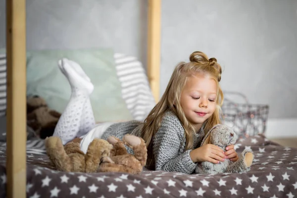 küçük kız yatakta yatarken oyuncak ayı ile oynarken