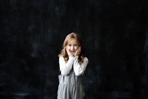 顔の表情と黒板の黒の背景に立っている女の子の肖像画 — ストック写真
