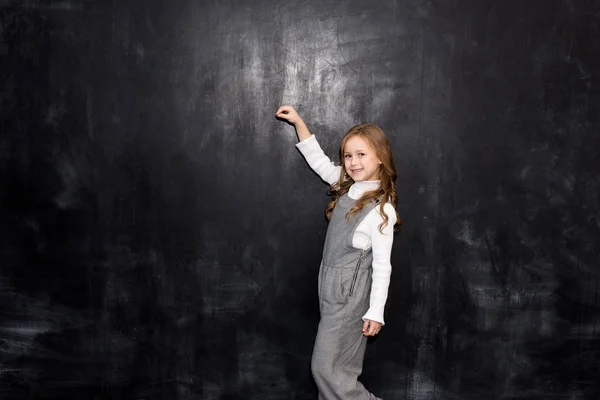 黒板にチョークで何かを書くかわいい女の子 — ストック写真