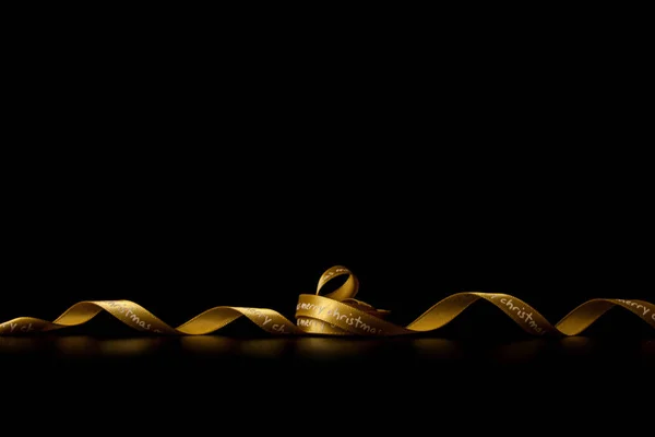 Golden ribbon on black background. Christmas decoration backgrou