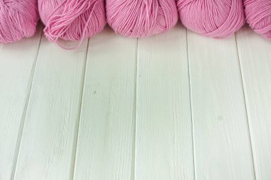 İplik örgü topları içine haddelenmiş Beyaz ahşap zemin üzerinde. 