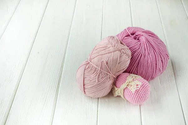 Fios de tricô rosa claro enrolados em bolas em um bac de madeira branco — Fotografia de Stock