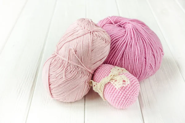 Fios de tricô rosa claro enrolados em bolas em um bac de madeira branco — Fotografia de Stock
