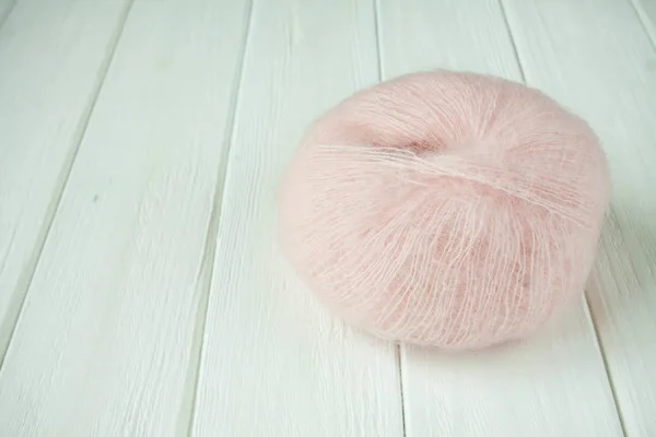 Knitting yarn rolled into balls on a white wooden background.