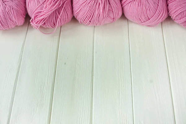 Knitting yarn rolled into balls on a white wooden background.