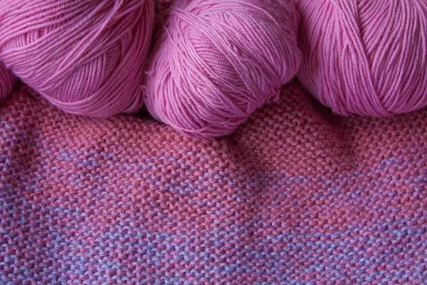 Fils à tricoter roulés en boule sur un fond tricoté . — Photo