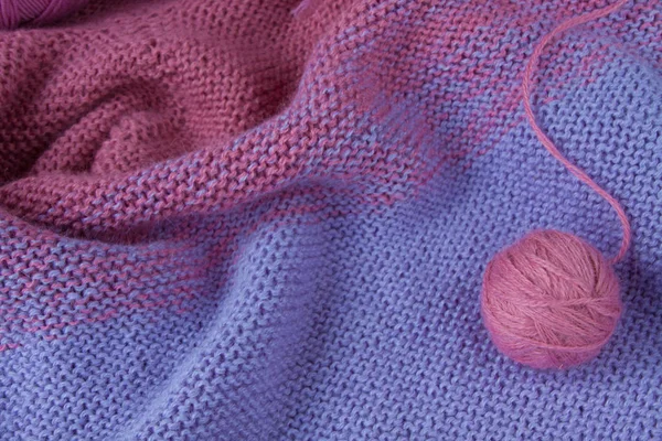 Knitting yarn rolled into ball on a knitted background.