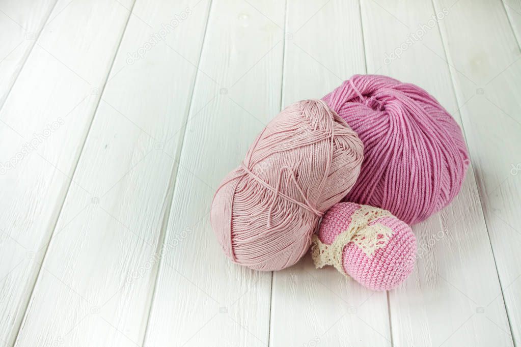 Light pink knitting yarn rolled into balls on a white wooden bac