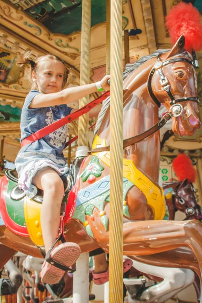 6 anos de menina no cavalo de brinquedo no parque de diversões — Fotografia de Stock