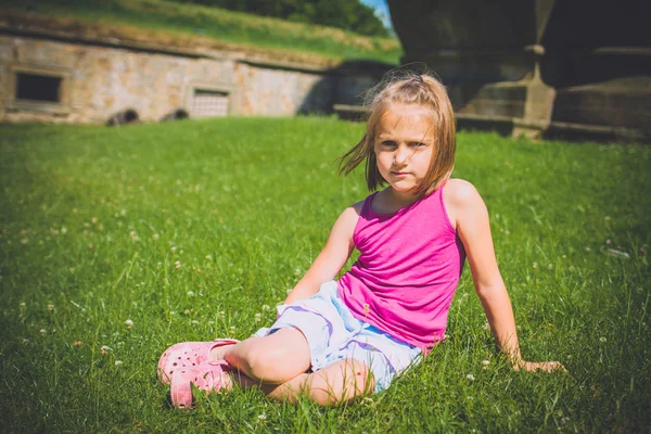 6 år flicka sitter i gräset utomhus — Stockfoto