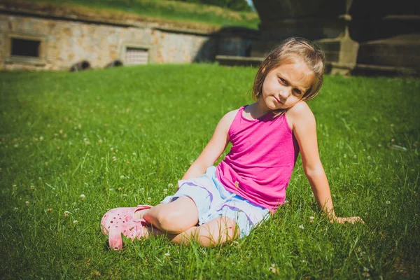 6 år flicka sitter i gräset utomhus — Stockfoto