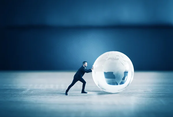 Empresario empujando una esfera de vidrio del mundo — Foto de Stock