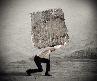 Businessman walking with a heavy boulder 