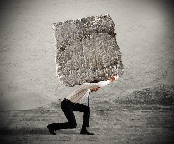 Businessman walking with a heavy boulder 
