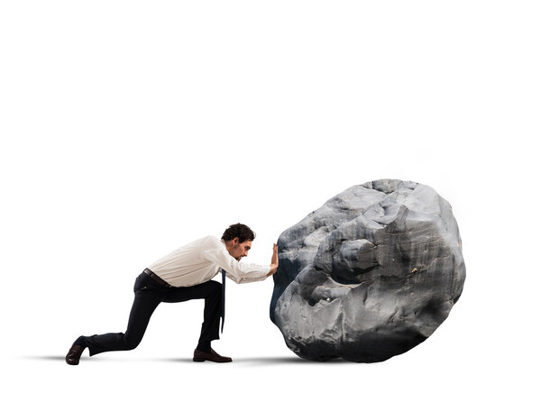 Businessman pushing a heavy boulder
