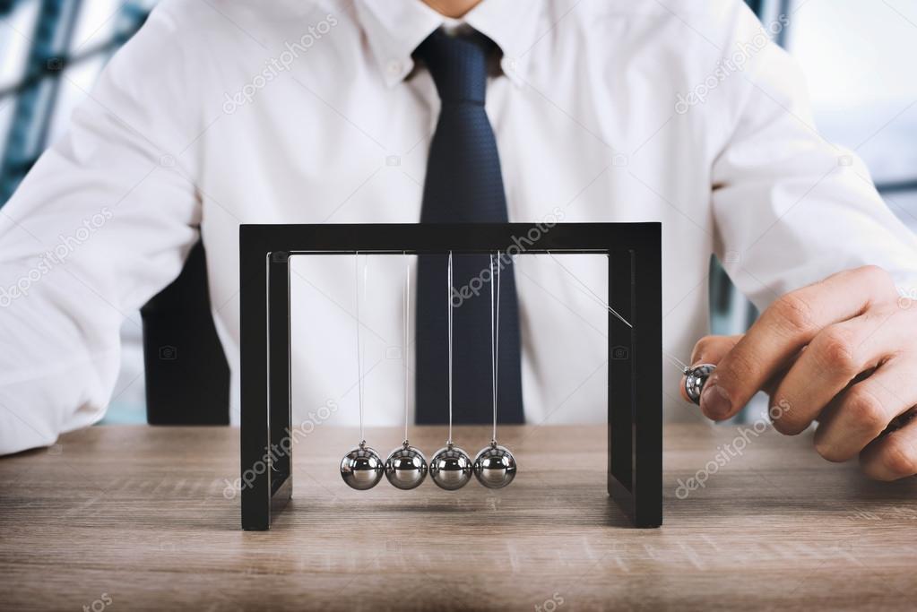 Businessman plays with the pendulum