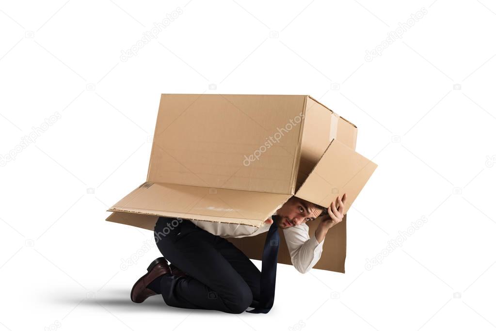 businessman is hiding under a cardboard