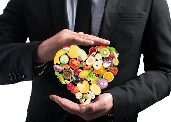 Homem detém um coração de legumes e frutas . — Fotografia de Stock