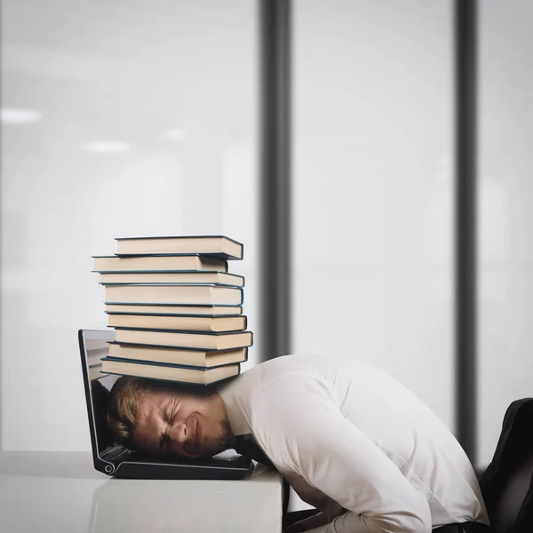 Businessman on laptop with a pile of books — Stock Photo, Image