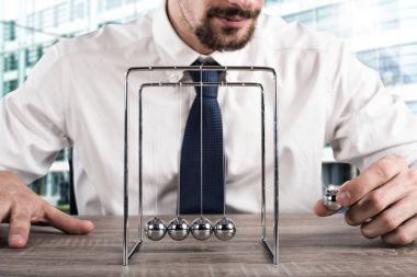 Businessman plays with the pendulum clipart