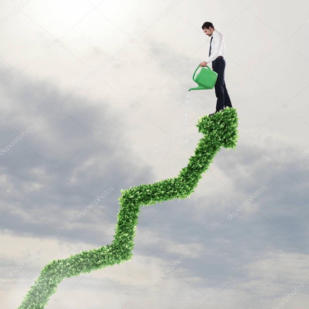 Businessman watering a big plant 