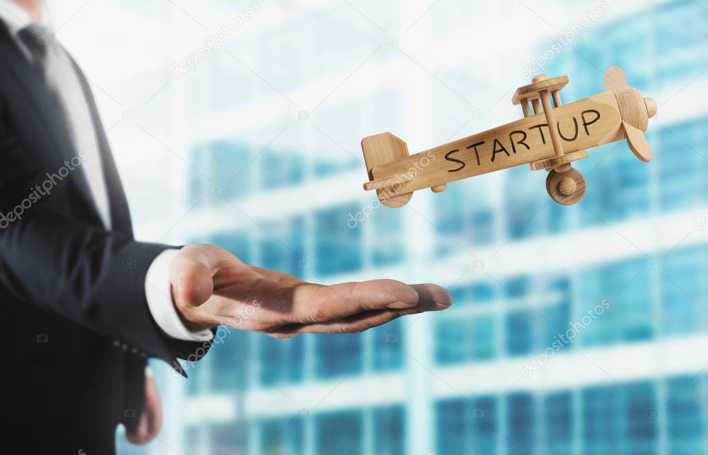 Businessman holding a small wooden aircraft. 