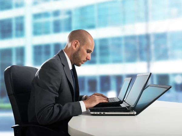 Hombre de negocios trabaja con tres portátiles i —  Fotos de Stock