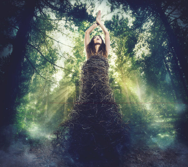 Woman dressed in branches in the woods. connection between nature and human concept