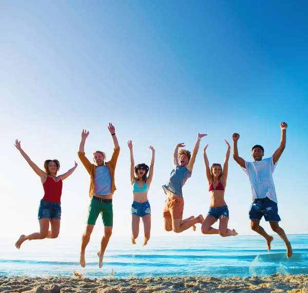 Felices amigos sonrientes saltando en la playa — Foto de Stock