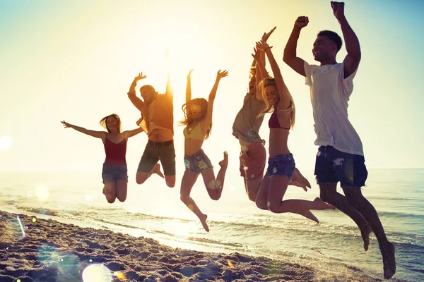 Lyckligt leende vänner hoppa på stranden — Stockfoto