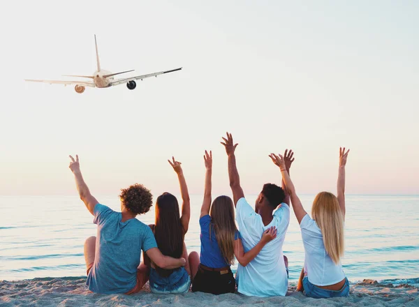 Group of friends having fun on the beach with flying aircraft — Stock Photo, Image
