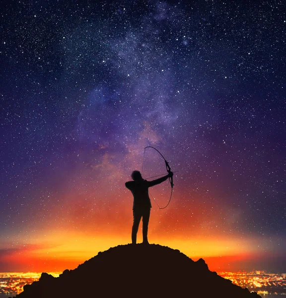 Empresário com arco no topo de uma montanha — Fotografia de Stock