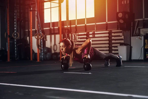 Chica hace ejercicio en el gimnasio con una kettlebells —  Fotos de Stock