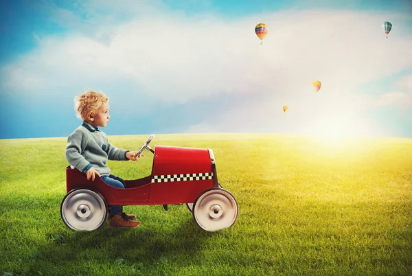 Child with car plays in a green field — Stock Photo, Image