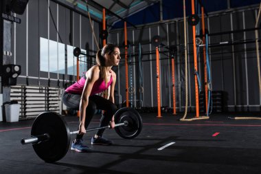 Spor salonunda bir halter ile atletik kız inşaat dışarı