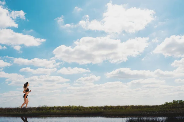 Courir fille sur un champ vert et ciel lumineux — Photo