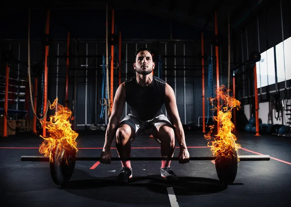 Homme athlétique travaille à la salle de gym avec un haltère ardent — Photo